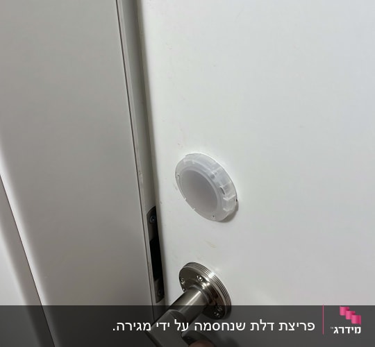 יד אוחזת בידית דלת מתכתית על דלת לבנה